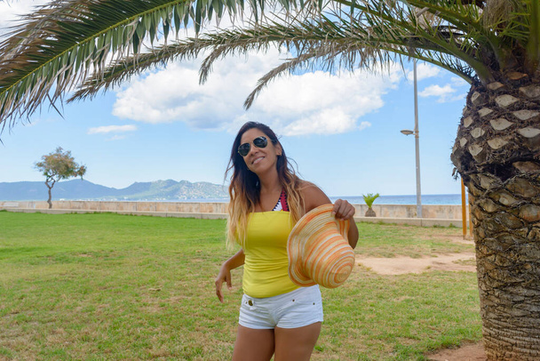 schöne und glückliche lateinische Frau mit langen Haaren, die lächelnd eine gute Zeit hat, im Urlaub auf Mallorca - Foto, Bild