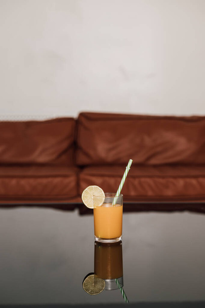 Un vaso de jugo de naranja está sobre una mesa negra de cristal - Foto, imagen