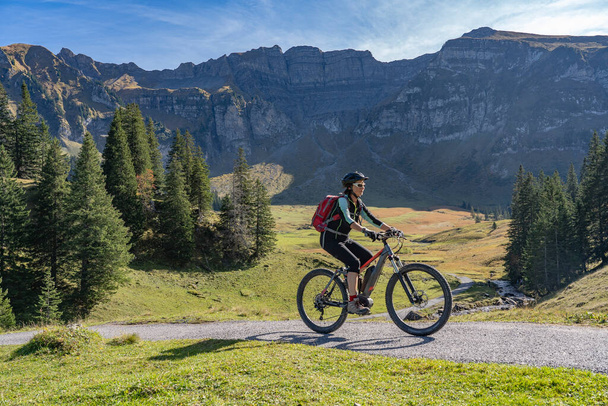Aktywna seniorka jeżdżąca na elektrycznym rowerze górskim w jesiennej atmosferze gór Puszczy Bregenckiej koło Mellau, Vorarlberg, Austria - Zdjęcie, obraz