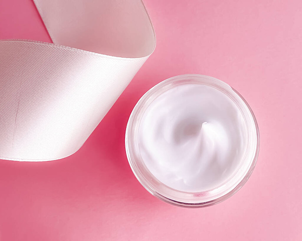 Skincare cosmetics, face cream moisturiser jar and white silk ribbon on pink background, beauty product flatlay close-up - Фото, изображение