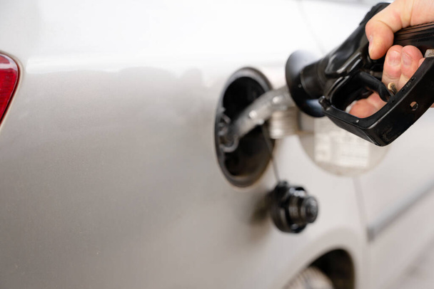 Muž plnící palivovou nádrž svého auta naftovým palivem na čerpací stanici zblízka, jako cena paliva stoupá - Fotografie, Obrázek