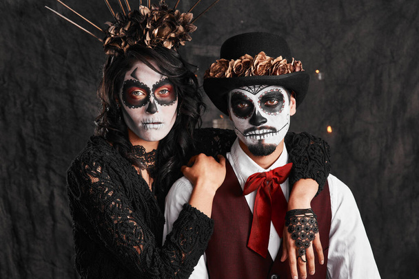 Slyšeli jsme oslavovat naše předky. Oříznutý portrét láskyplného mladého páru oblečeného v mexickém stylu halloween kostýmy. - Fotografie, Obrázek