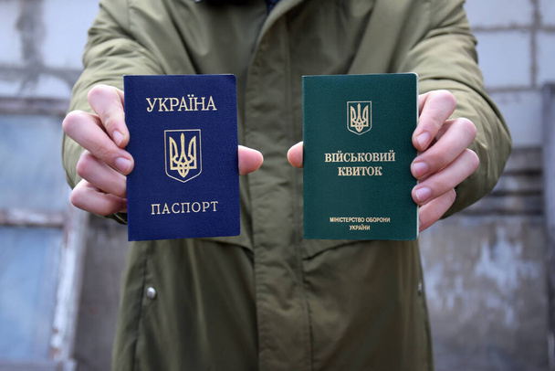 ウクライナ軍の身分証明書若い男の手の中にパスポート。ウクライナでの戦争。戦争を止めて. - 写真・画像