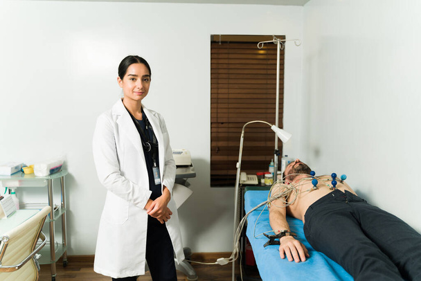 Retrato de una cardióloga y de una paciente a la que se le monitoriza la frecuencia cardíaca con un electrocardiograma - Foto, Imagen