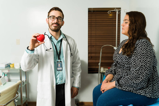 Prevención de problemas de salud. Retrato de un médico atractivo sonriendo mientras sostiene un corazón rojo sano  - Foto, Imagen