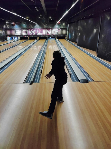 Genç bir çocuk bowling oynuyor, topu Skittles 'a atıyor. Arka plan - Fotoğraf, Görsel