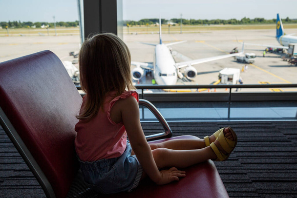 Little girl watches plane at the airport - 写真・画像