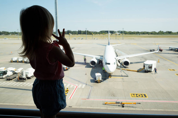 A kislány repülőt néz a reptéren. - Fotó, kép