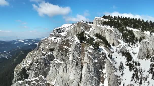 Vista aérea del dron de los Cárpatos de primavera, Rumania. Picos rocosos y valles parcialmente cubiertos de bosque de nieve - Metraje, vídeo
