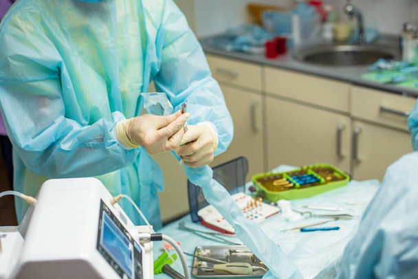 Professional dentist holding stomatological tool near the table with dental instruments in hospital during surgery - Valokuva, kuva