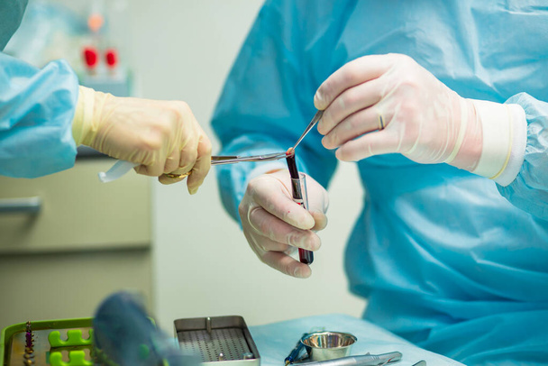 Professional dentist holding stomatological tool in hospital during surgery - Φωτογραφία, εικόνα