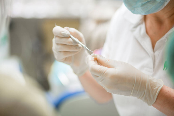 Επαγγελματίας οδοντίατρος που κατέχει στοματολογικό εργαλείο στο νοσοκομείο κατά τη διάρκεια χειρουργικής επέμβασης - Φωτογραφία, εικόνα
