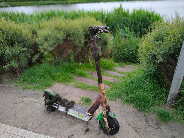 Trendy электрический скутер, стоящий на берегу озера после того, как его вытащили из воды. - Фото, изображение