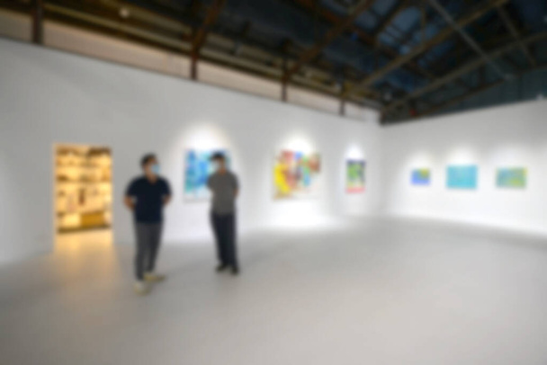 People looking at paintings on white wall in Art exhibition gallery. Blurry background. - Photo, Image