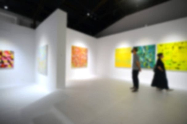 Gente mirando pinturas en la pared blanca en la galería de exposiciones de arte. Fondo borroso. - Foto, Imagen