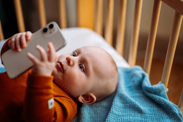 Egy kisbaba okostelefonnal. Videó megtekintése okostelefonon. - Fotó, kép