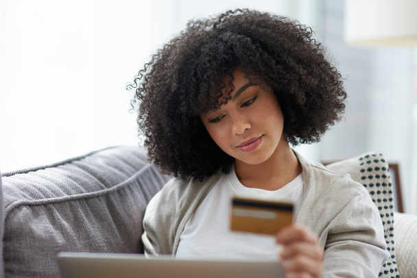 Zakupy online są o wiele wygodniejsze. Zdjęcie młodej kobiety używającej laptopa i karty kredytowej w domu. - Zdjęcie, obraz