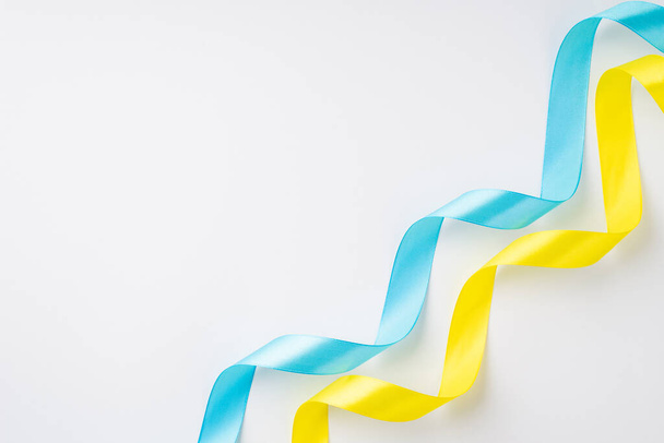 Stop the war in Ukraine concept. Top view photo of national flag colors yellow and blue wavy silk ribbons on isolated white background with empty space - Foto, imagen