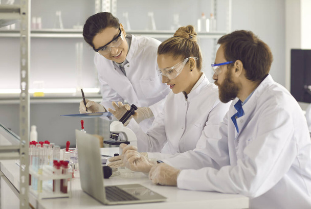 Group of young scientists working in a modern pharma or biotech science laboratory - Fotoğraf, Görsel