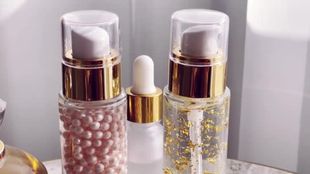 Kosmetyki do pielęgnacji i makijażu, złote butelki emulsji serum i perfumy, produkty kosmetyczne zbliżenie - Materiał filmowy, wideo