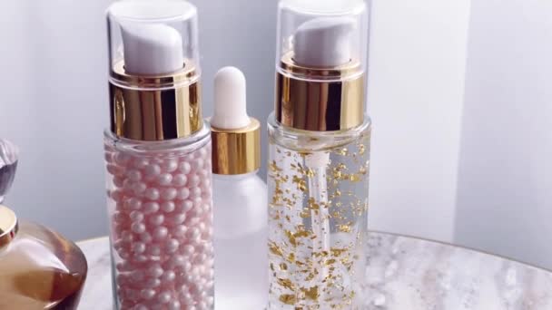 Cuidado de la piel y cosméticos de maquillaje, botellas de emulsión de suero de oro y perfume, productos de belleza de cerca - Metraje, vídeo