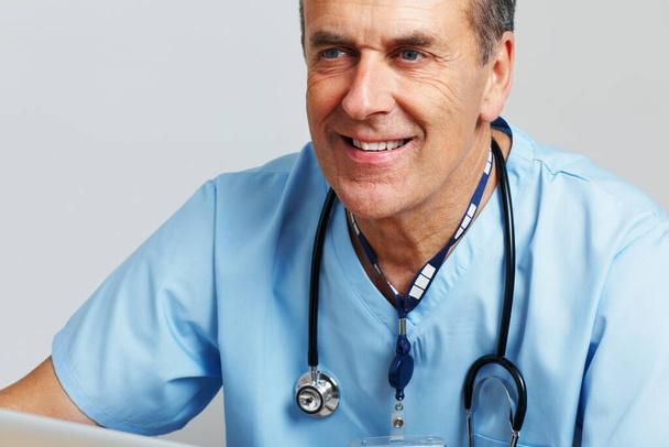 Happy senior doctor with stethoscope against white background. Closeup portrait of a senior doctor with stethoscope against white background. - Photo, Image