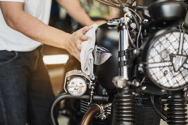 自転車を掃除するバイカーガレージで燃料タンクの研磨とコーティングワックス。オートバイのメンテナンスと修理の概念. - 写真・画像