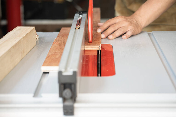 Tischler verwenden Stoßstangen oder Schubblöcke auf Tischsäge, Stoßstangen kontrollieren Holz, halten Hände und Finger vor dem Sägeblatt sicher, Holzbearbeitungskonzept. Selektiver Fokus - Foto, Bild