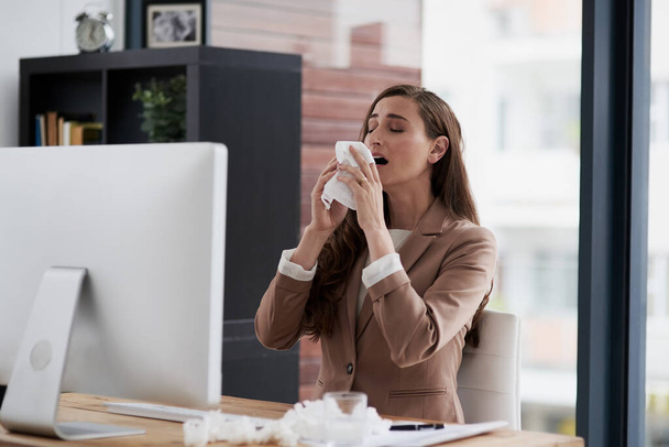 Zu viele Niesen unterbrechen ihren Weg zum Erfolg. Aufnahme einer an Allergien leidenden jungen Geschäftsfrau bei der Arbeit. - Foto, Bild