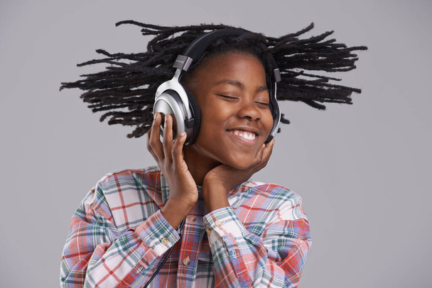 Whipping to the beat. An African-American boy listening to music over his headphones. - Foto, imagen