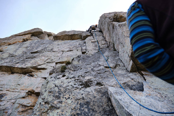 Альпинист достигает вершины, в то время как его партнер страхует его - Фото, изображение