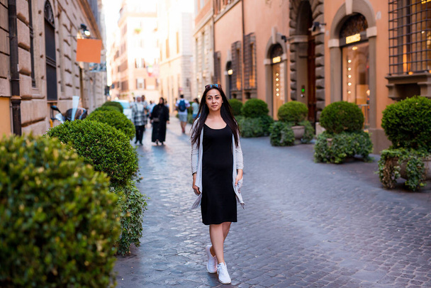 Mujer bonita joven en vestido de moda elegante caminando por la calle en Roma en el día soleado. Vacaciones y moda femenina ciudad concepto de estilo de vida - Foto, imagen