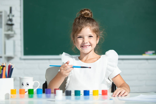 Child girl at school draws with paints. Kids artist creativity. Funny kids emotions. - Zdjęcie, obraz