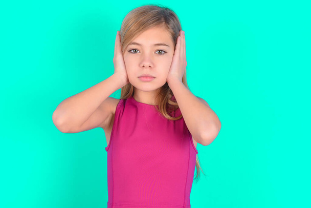 Розмальована маленька кавказька дівчинка, що вимикає вуха руками, не хоче слухати хард-рок, шум або гучну музику. - Фото, зображення