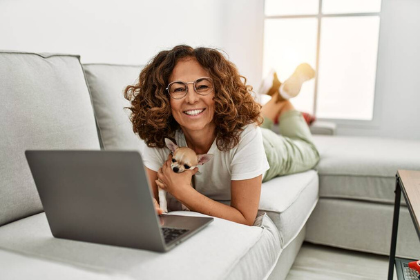 Middle age hispanic woman smiling confident using laptop at home - Zdjęcie, obraz