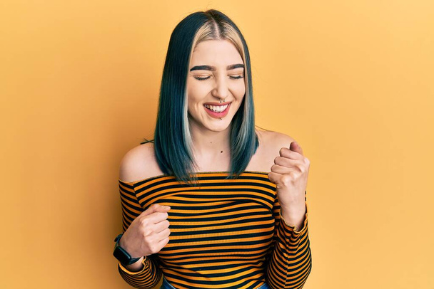Young modern girl wearing casual striped shirt celebrating surprised and amazed for success with arms raised and eyes closed  - Photo, Image