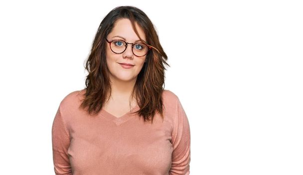 Young plus size woman wearing casual clothes and glasses relaxed with serious expression on face. simple and natural looking at the camera.  - Foto, afbeelding