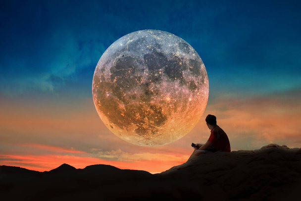Giovane uomo sta guardando la luna piena su un bel tramonto. - Foto, immagini
