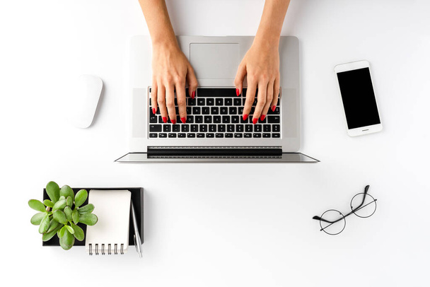 Overhead shot of woman hands working on laptop on white table with accessories. Office desktop. Flat lay - Fotoğraf, Görsel