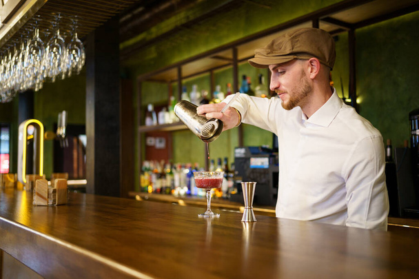 Bärtiger Barkeeper bereitet Cocktail in Kneipe zu - Foto, Bild