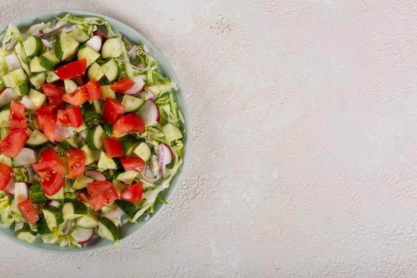 Salat aus Tomaten und Gurken und verschiedene rohe Gemüsesorten mit Olivenöl. Konzept einer gesunden vegetarischen Ernährung - Foto, Bild