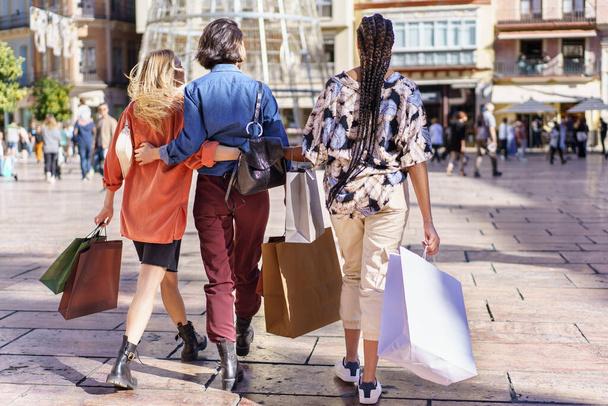 Anonymní stylové dámy kráčející po náměstí s nákupními taškami - Fotografie, Obrázek