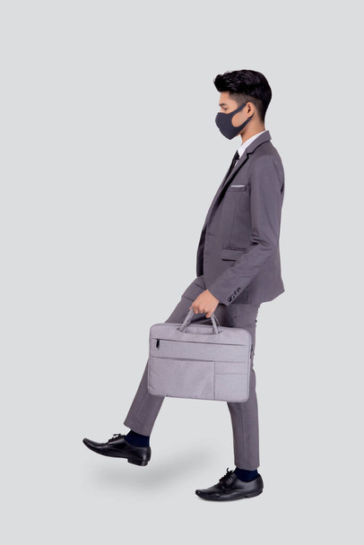 Portrait young asian businessman in suit wearing face mask walk step for protective covid-19 isolated on white background, business man and healthcare, quarantine for pandemic coronavirus, new normal. - Foto, Imagen