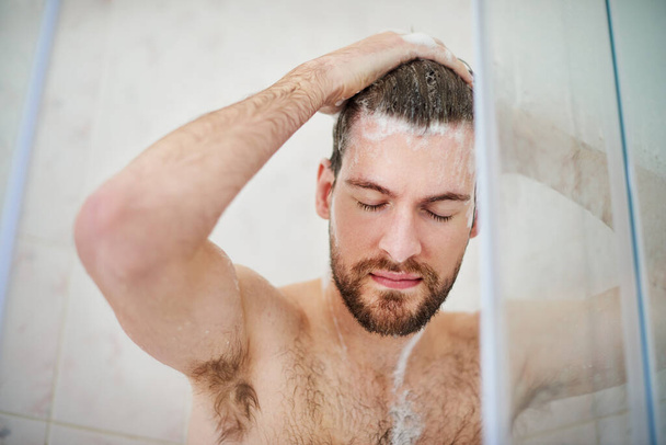 Begin uw dag met een verfrissende noot. Gehakte foto van een knappe jongeman die thuis een douche heeft. - Foto, afbeelding