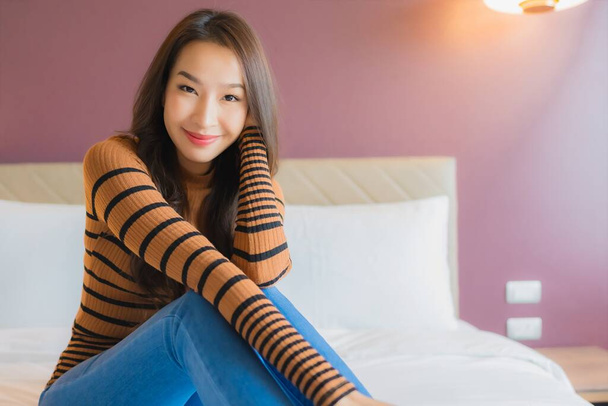 Ritratto bella giovane donna asiatica sorriso rilassarsi sul letto in camera da letto interno - Foto, immagini