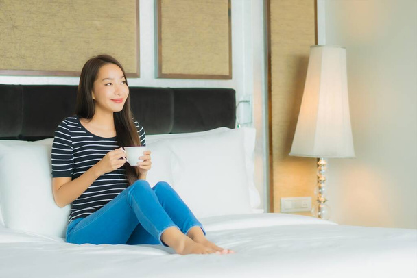 Portré gyönyörű fiatal ázsiai nő mosoly pihenjen az ágyon a hálószoba belső - Fotó, kép