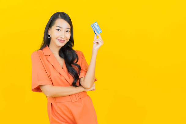 Porträt schöne junge asiatische Frau lächeln mit Kreditkarte auf gelbem Hintergrund - Foto, Bild