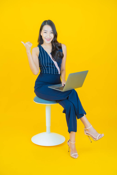 Ritratto bella giovane donna asiatica sorriso con computer portatile su sfondo isolato - Foto, immagini
