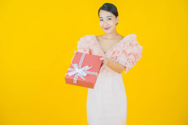 Portrait beautiful young asian woman smile with red gift box on color background - Photo, Image