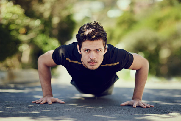 Getting stonger. Full length portrait of a handsome young man doing pushups outdoors. - Foto, Imagem